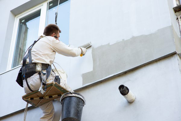 Painter on a suspended platform painting a building facade