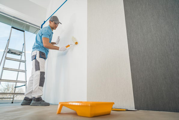 Painter rolling white paint on an interior wall