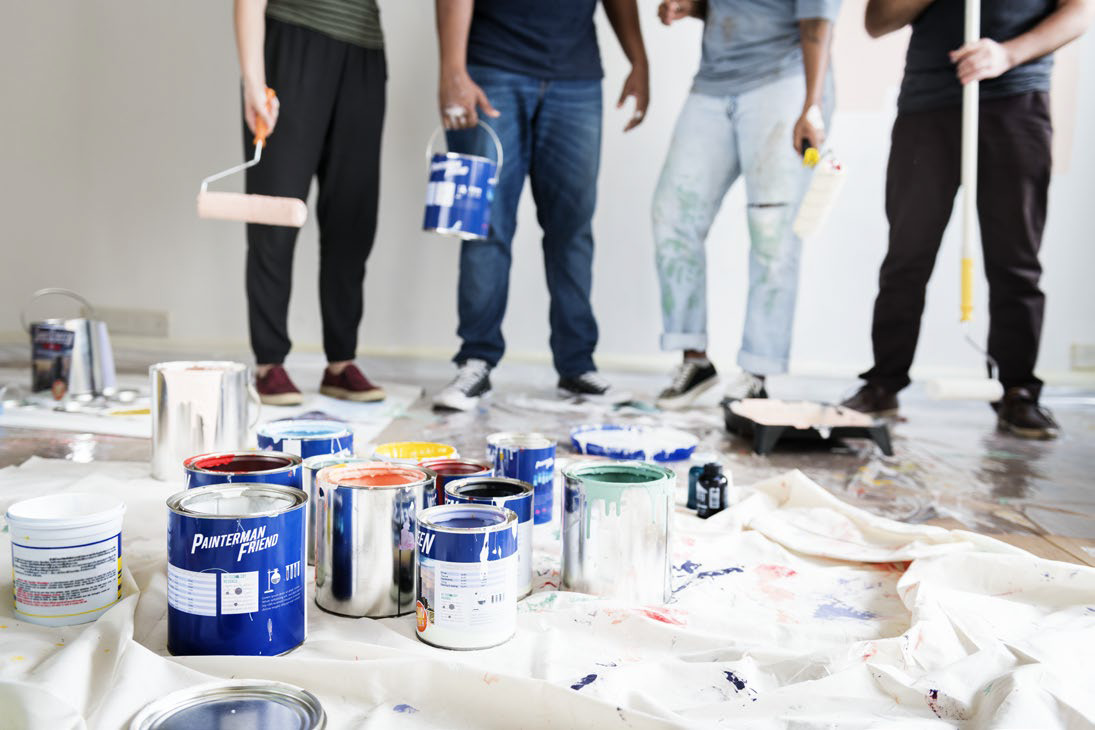 Painting crew with rollers and paint tins on a drop cloth